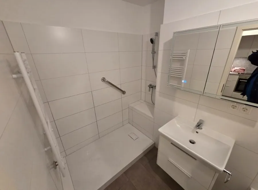 Fertig saniertes Bad mit bodengleicher Dusche, Sitzbank, Haltegriff und Waschtisch